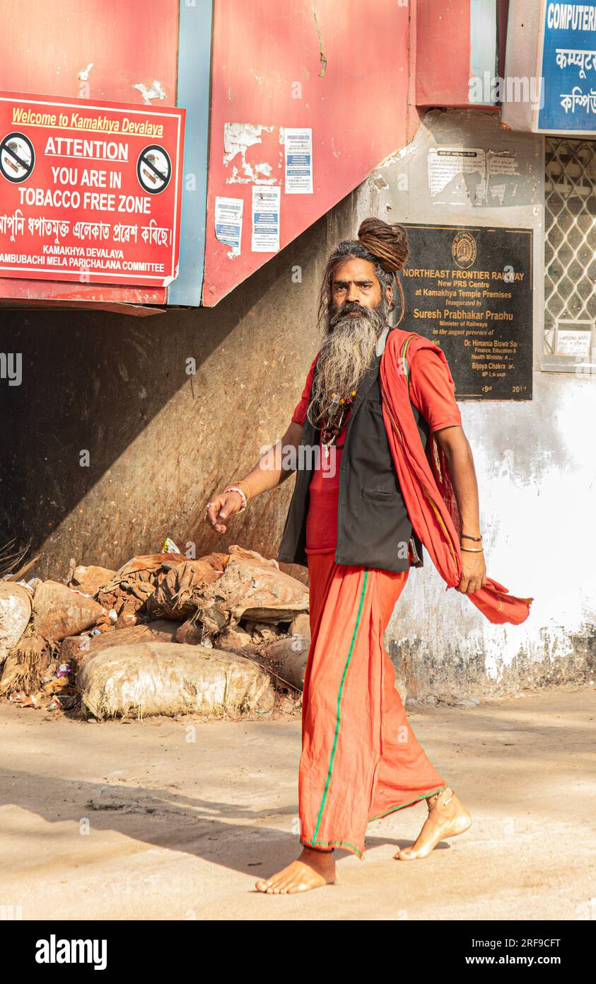 Un santo indù che indossa abiti tradizionali e un grande topknot che cammina nella periferia dell'area del tempio Kamakya Devalaya a Guwahati, Assam, India Foto Stock