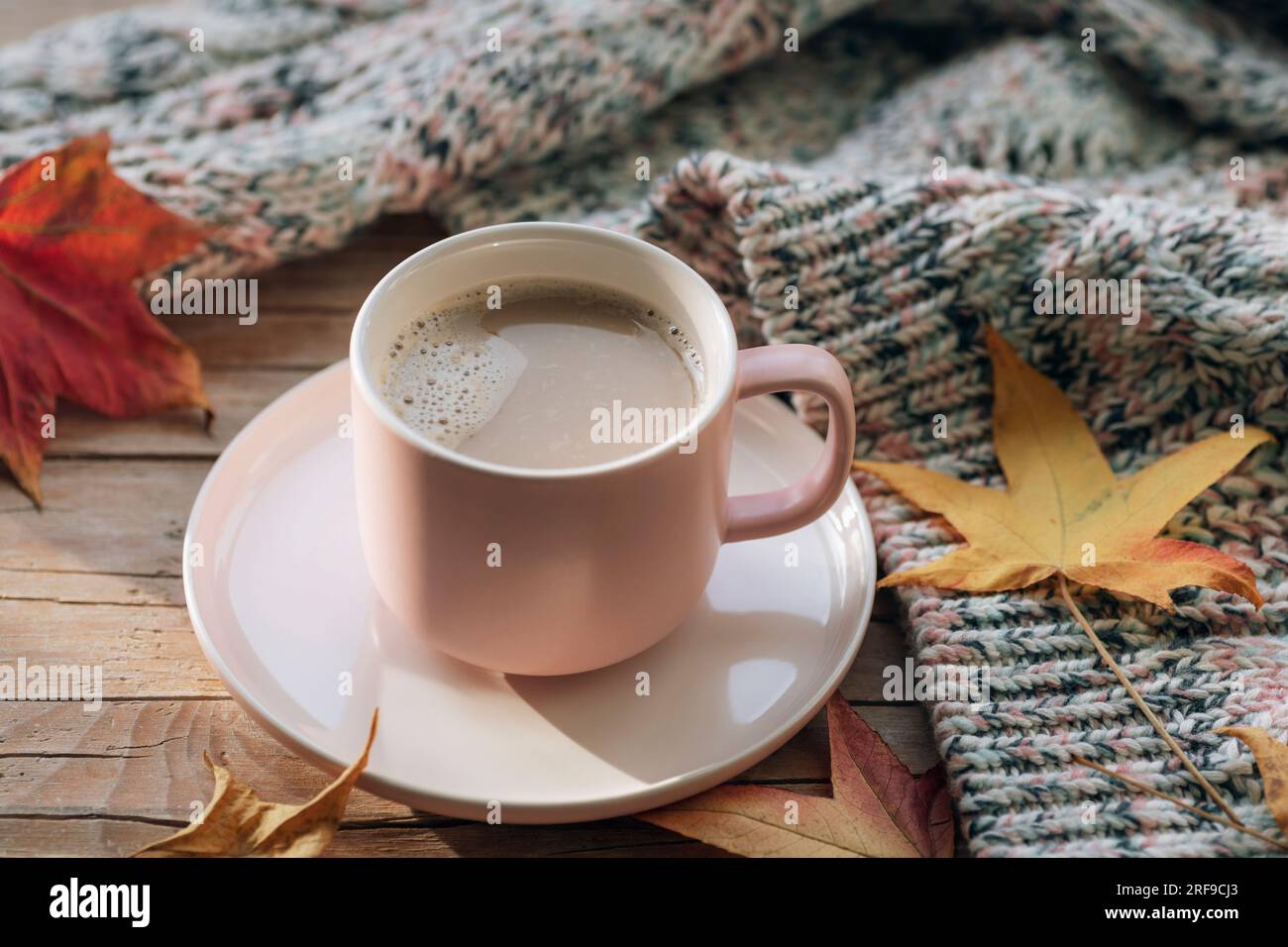 Tazza da caffè, foglie autunnali e maglione a maglia su tavolo di legno. Concetto autunnale. Vista dall'alto. Foto Stock