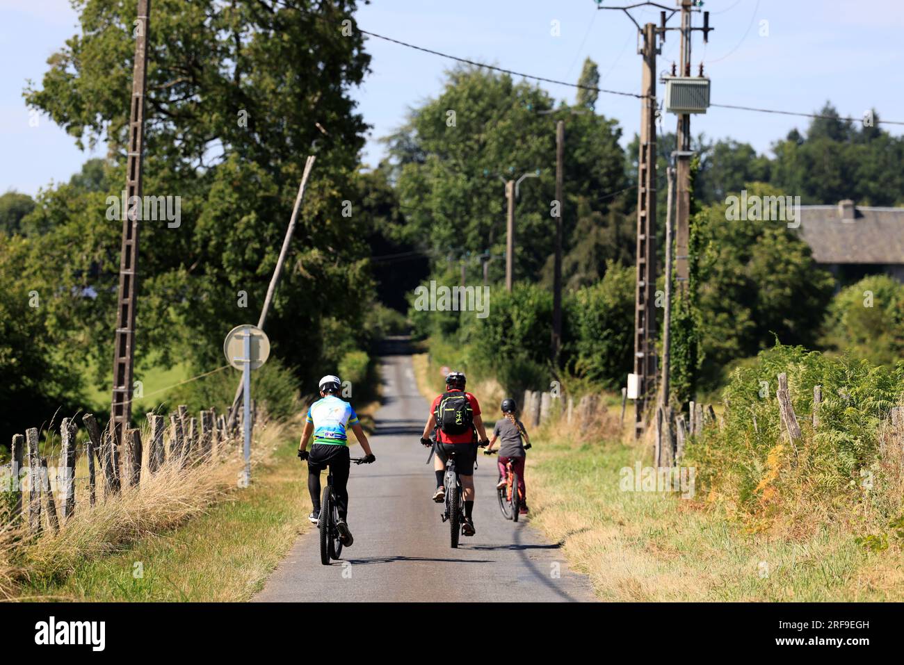 Promenade en vélo d’un père, de son fils et de sa fille sur une petite Route de campagne en Corrèze dans le Limousin, Francia, Europa Foto Stock
