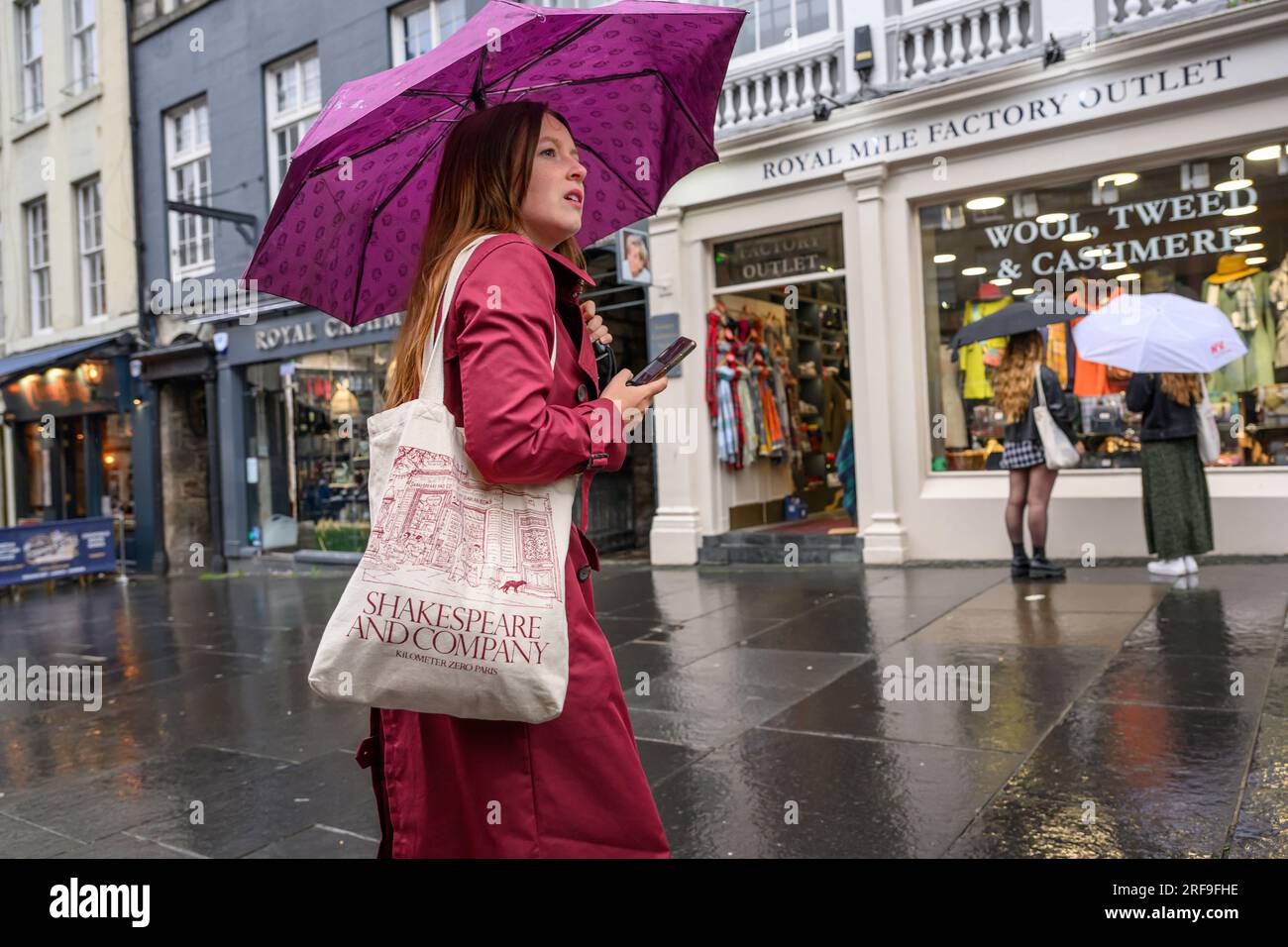 Shopper with Broken Umbrella & Mobile Phone on A Rainy Day on High Street, The Royal Mile, Edimburgo, Scozia, Regno Unito, REGNO UNITO Foto Stock