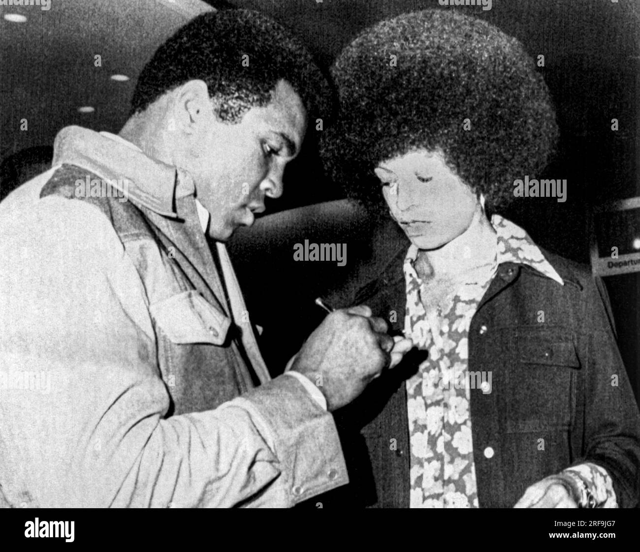 New York, New York 9 settembre 1974 Muhammad Ali e Angela Davis si scambiano autografi quando si incontrano all'aeroporto la Guardia. Ali stava andando nello Zaire per combattere contro George Foreman, Foto Stock