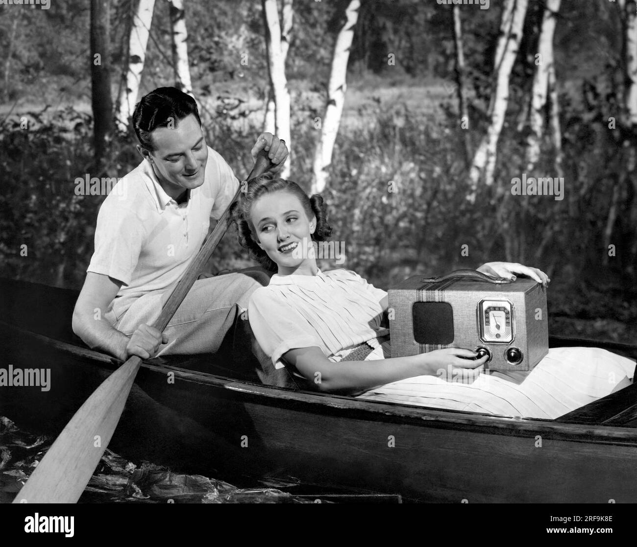 Stati Uniti: c. 1935. Due amanti in canoa che ascoltano una radio portatile. Foto Stock