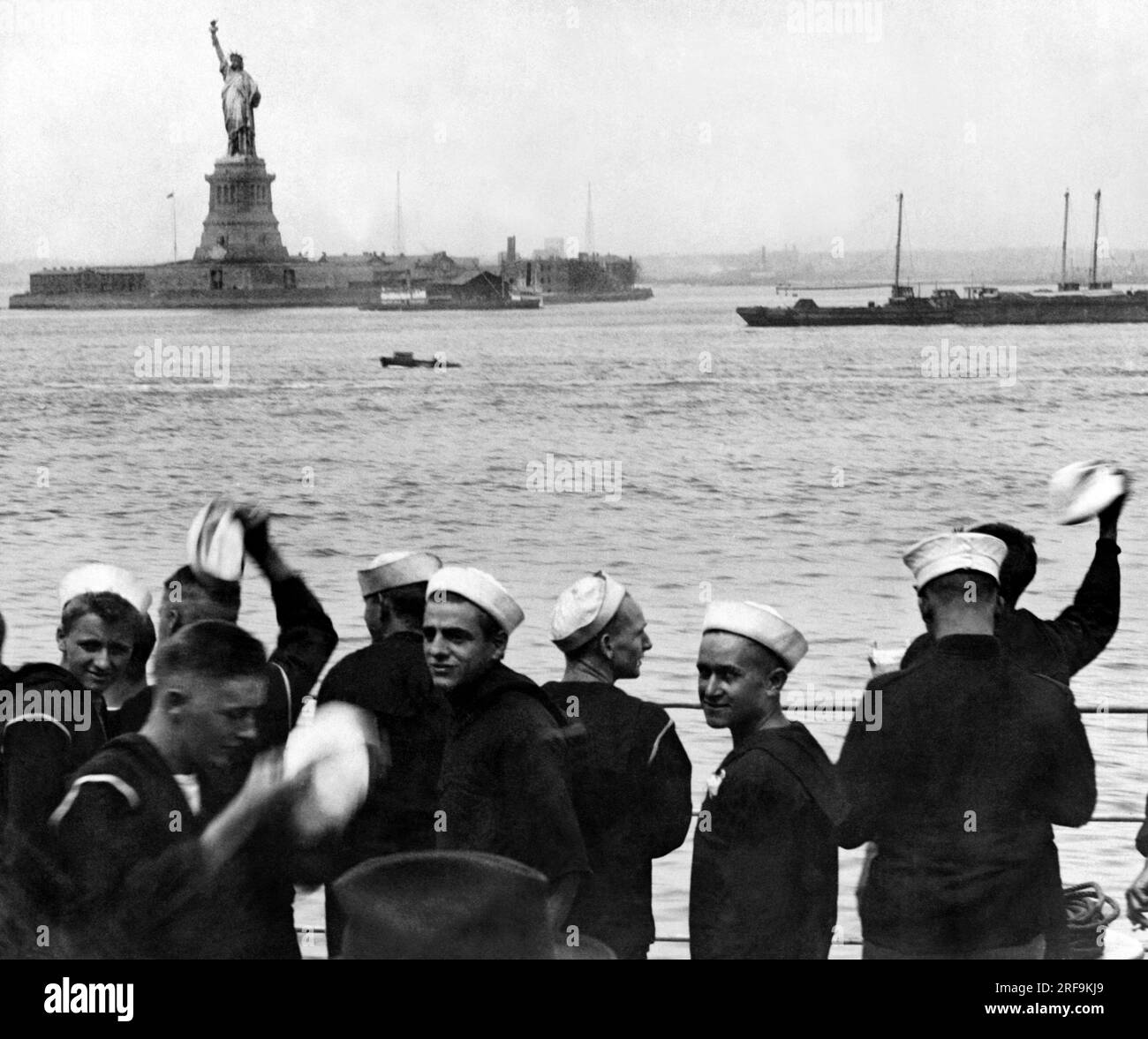 New York, New York: 1 maggio 1920. I marinai a bordo della USS Pennsylvania salutano mentre passano davanti alla Statua della libertà durante il viaggio verso il porto di New York. Significa letteralmente libertà per loro, in quanto riceveranno loro un permesso di terra quando finalmente ancoreranno. Foto Stock