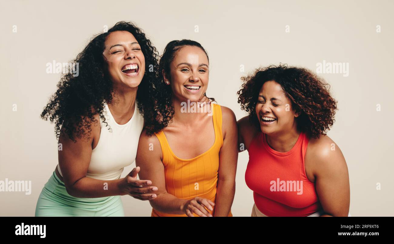 Allegro gruppo di tre giovani e diverse atleti femminili celebrano la loro amicizia e il loro stile di vita sano indossando abbigliamento fitness in uno studio. SP Foto Stock