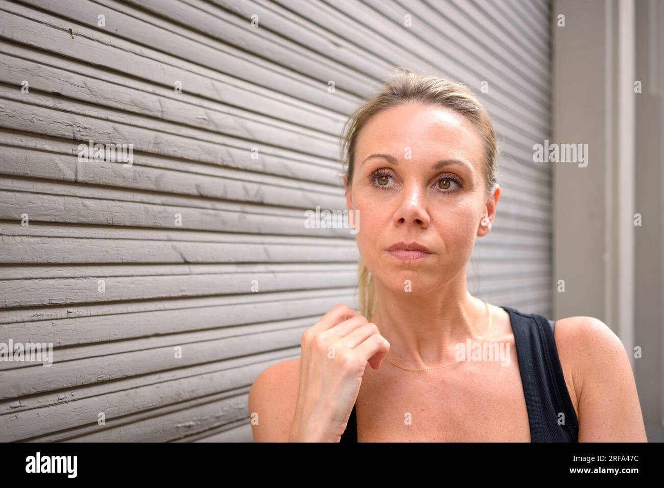 Ritratto frontale di una bella donna davanti a una porta a rulli Foto Stock