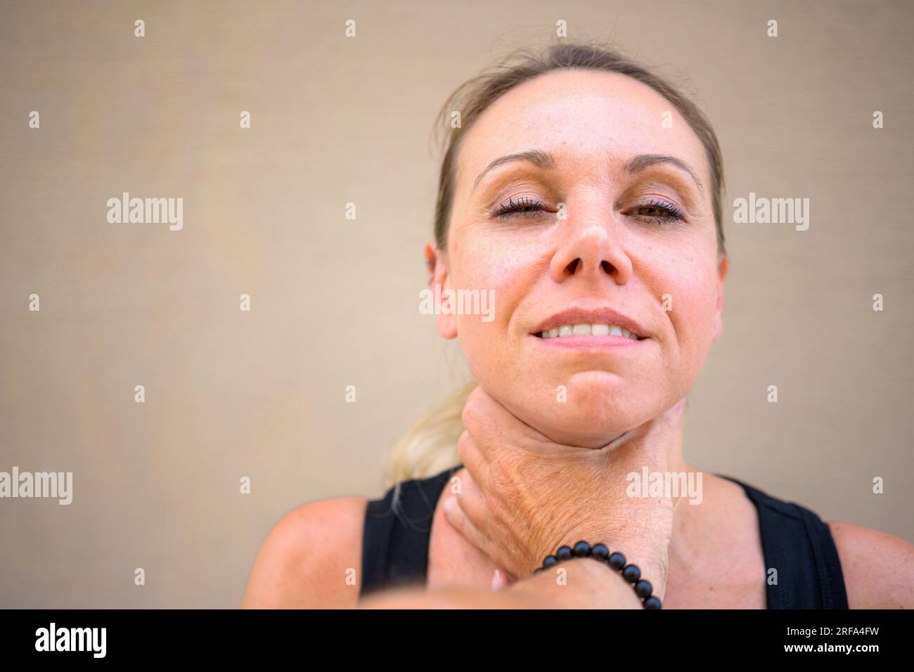 Una donna molto attraente con un sorriso malizioso guarda la telecamera  mentre la mano di uno sconosciuto è sul collo Foto stock - Alamy