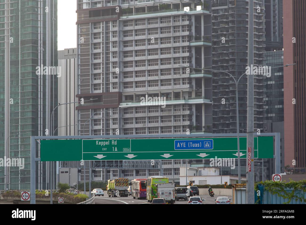 Un enorme cartello verde indica il nome della strada nella direzione in cui si dirigono i conducenti. Essere un autista cortese e paziente sulla strada. Singapore Foto Stock