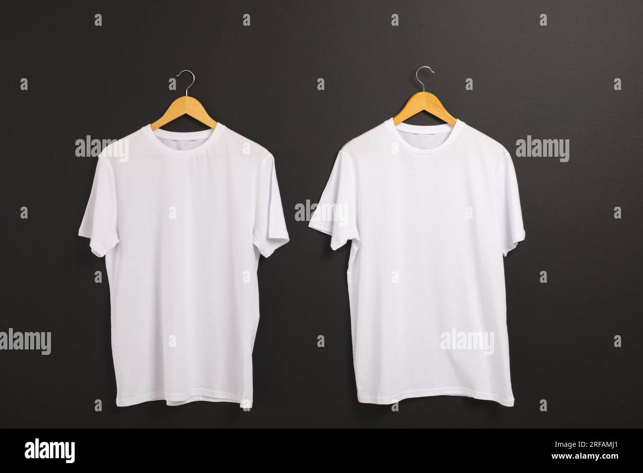 Due t-shirt bianche su appendiabiti e spazio per la copia su sfondo nero Foto Stock