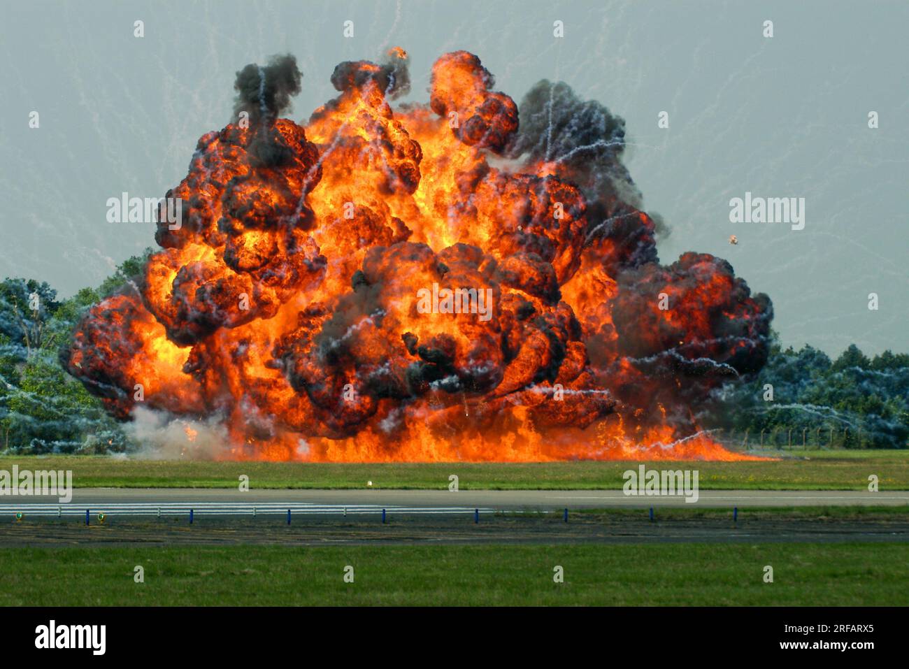 Enorme eruzione di fuoco, esplosione pirotecnica. Fiamme. Fuoco caldo e fumo nero intenso. Simulando l'esplosione di una bomba da uno scenario di attacco al campo d'aviazione Foto Stock