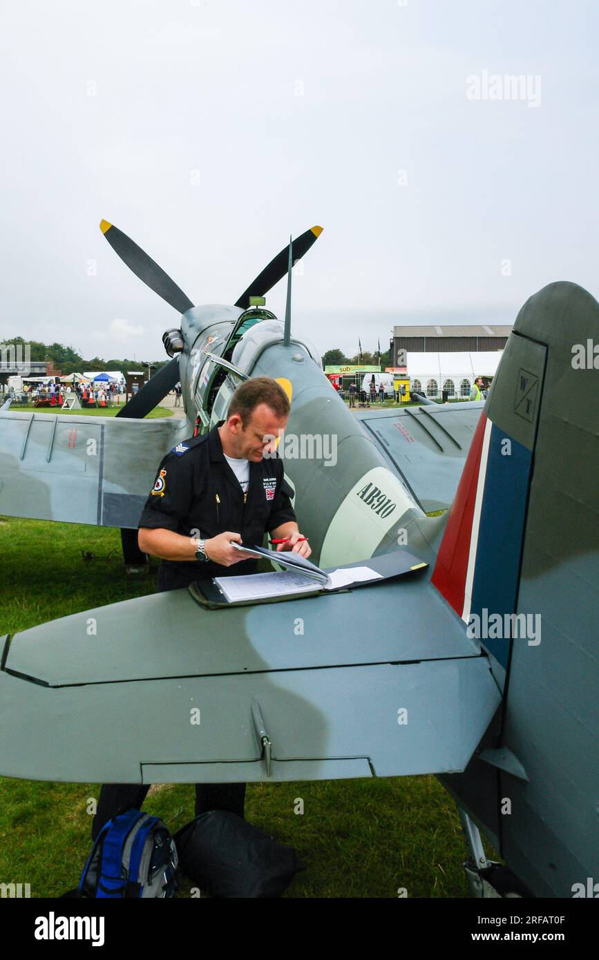 RAF Battle of Britain Memorial Flight Crew compilando i documenti sull'ala posteriore del Supermarine Spitfire Vb secondo aereo da combattimento della guerra mondiale AB910 Foto Stock