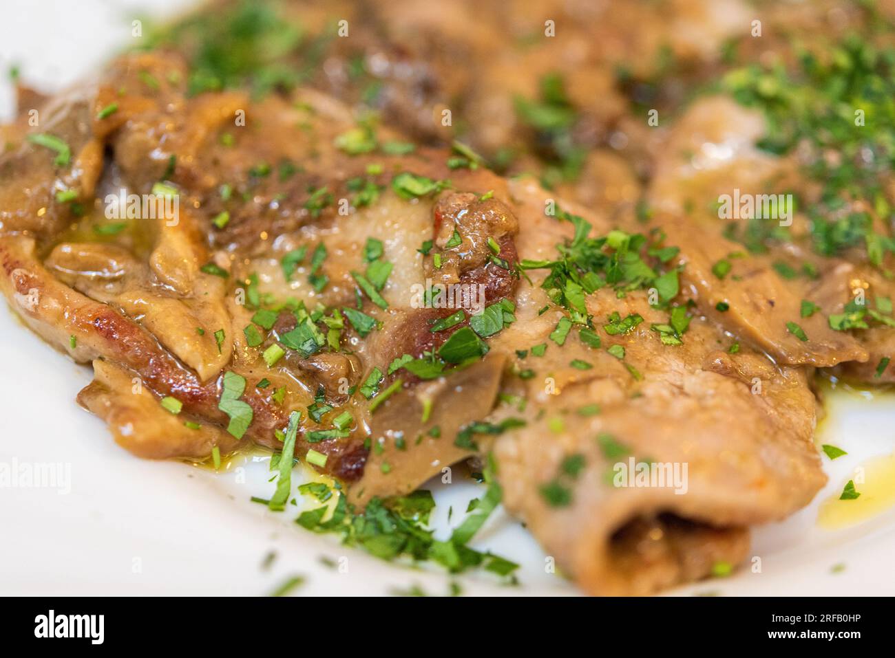 Tradizionale piatto di vitello servito a Roma, Italia, su un piatto bianco condito con erbe. Foto Stock