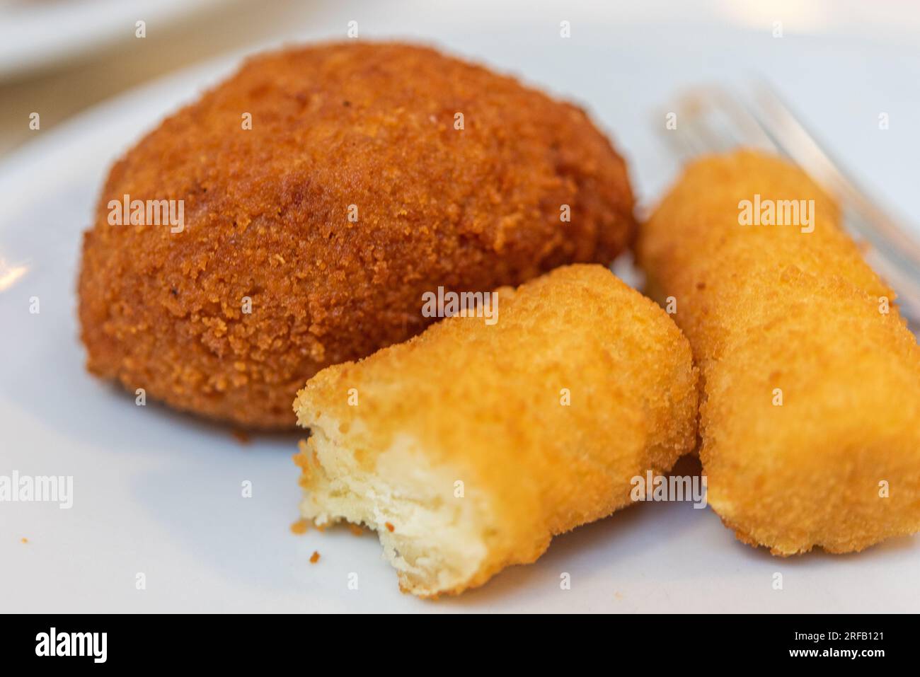 Palla di patate fritte e riso servita come antipasto a Roma, in Italia, su piatto bianco e con forchetta. Foto Stock