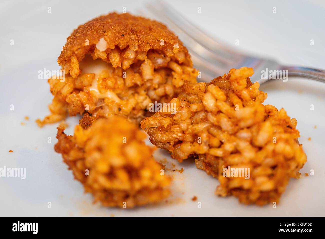 Palla di riso fritta servita come antipasto a Roma, in Italia, su piatto bianco e con forchetta. Foto Stock