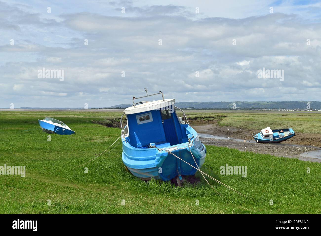 Ci sono tre barche blu tutte ormeggiate nella palude vicino alla stretta area del fiume proprio accanto a Penclawdd all'inizio della penisola di Gower. Foto Stock