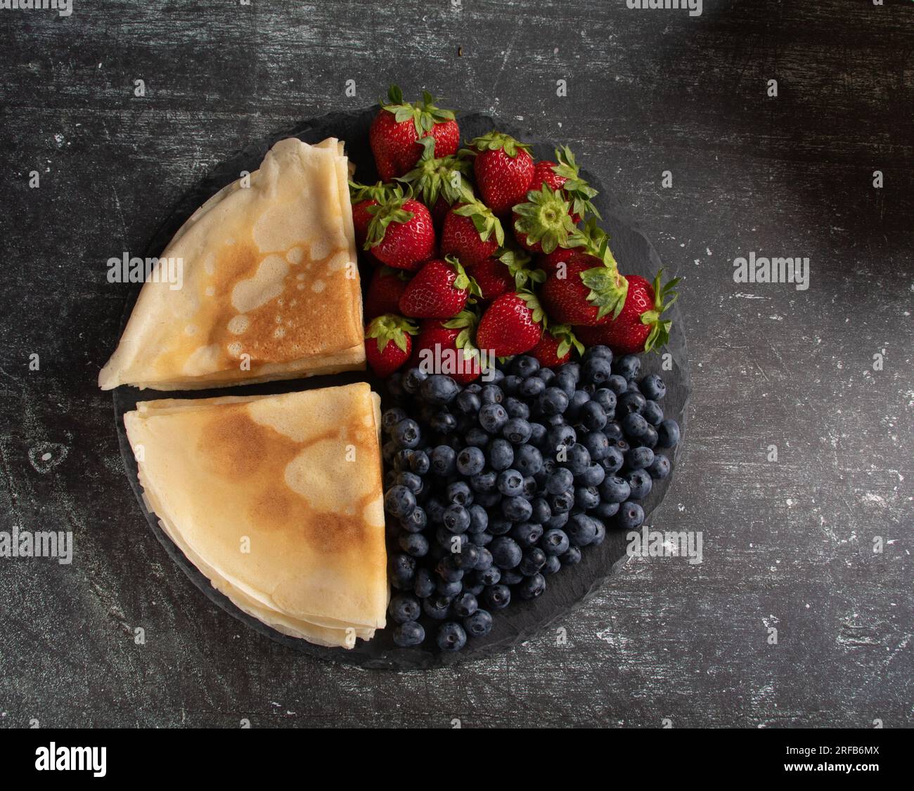 foto frittelle sottili con mirtilli e fragole su un piatto, foto orizzontale, vista dall'alto Foto Stock