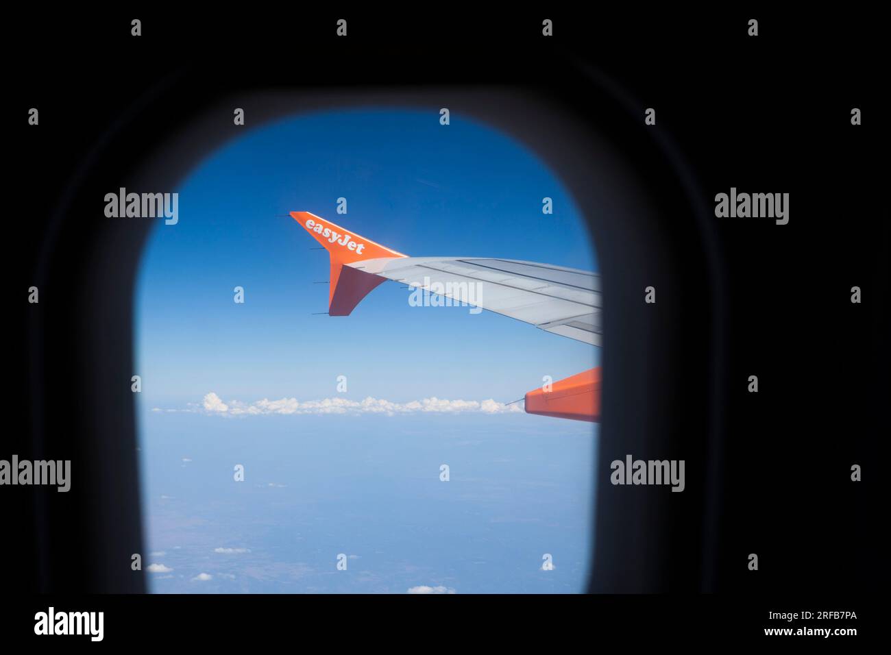 Vista dalla finestra di un aereo o di un aereo di linea che mostra l'ala del jet e un cielo blu profondo. Foto Stock