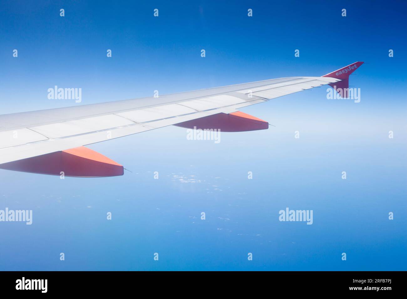 Vista dalla finestra di un aereo o di un aereo di linea che mostra l'ala del jet e un cielo blu profondo. Foto Stock