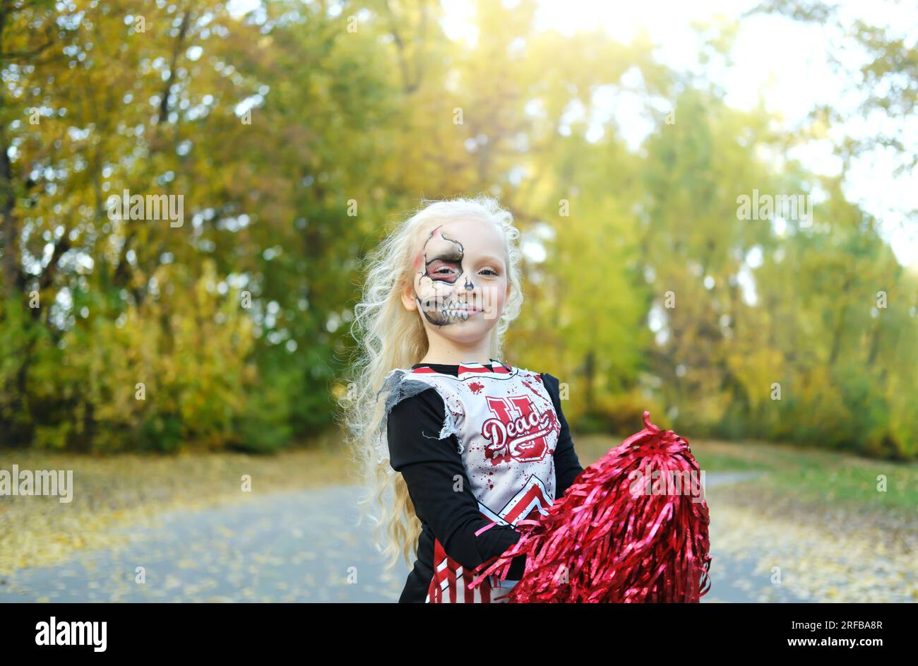 Una ragazza con un costume da cheerleader e un trucco a mezza faccia sotto  forma di scheletro celebra Halloween. Foto orizzontale Foto stock - Alamy