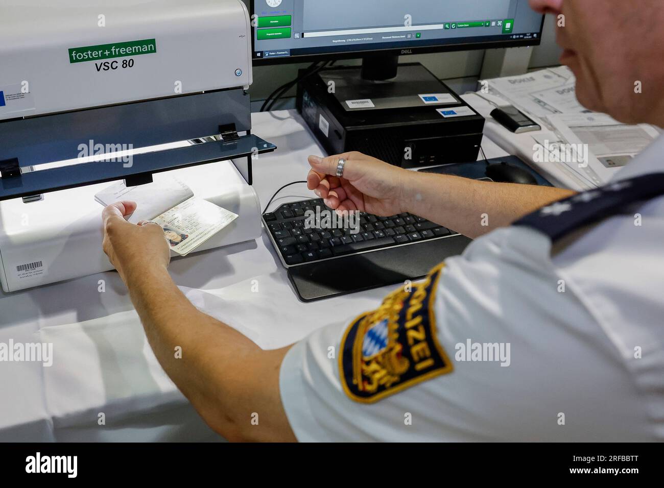 02 agosto 2023, Baviera, Norimberga: Un agente di polizia della polizia di frontiera bavarese verifica l'autenticità di una carta d'identità all'aeroporto, risulta essere un falso. La polizia di frontiera ha iniziato il suo lavoro il 1 luglio 2018. Foto: Daniel Löb/dpa Foto Stock