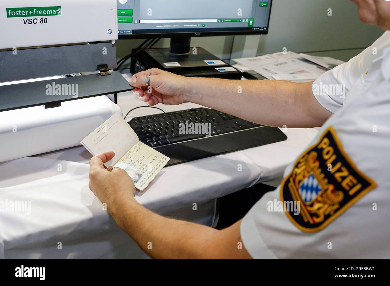 02 agosto 2023, Baviera, Norimberga: Un agente di polizia della polizia di frontiera bavarese verifica l'autenticità di una carta d'identità all'aeroporto, risulta essere un falso. La polizia di frontiera ha iniziato il suo lavoro il 1 luglio 2018. Foto: Daniel Löb/dpa Foto Stock