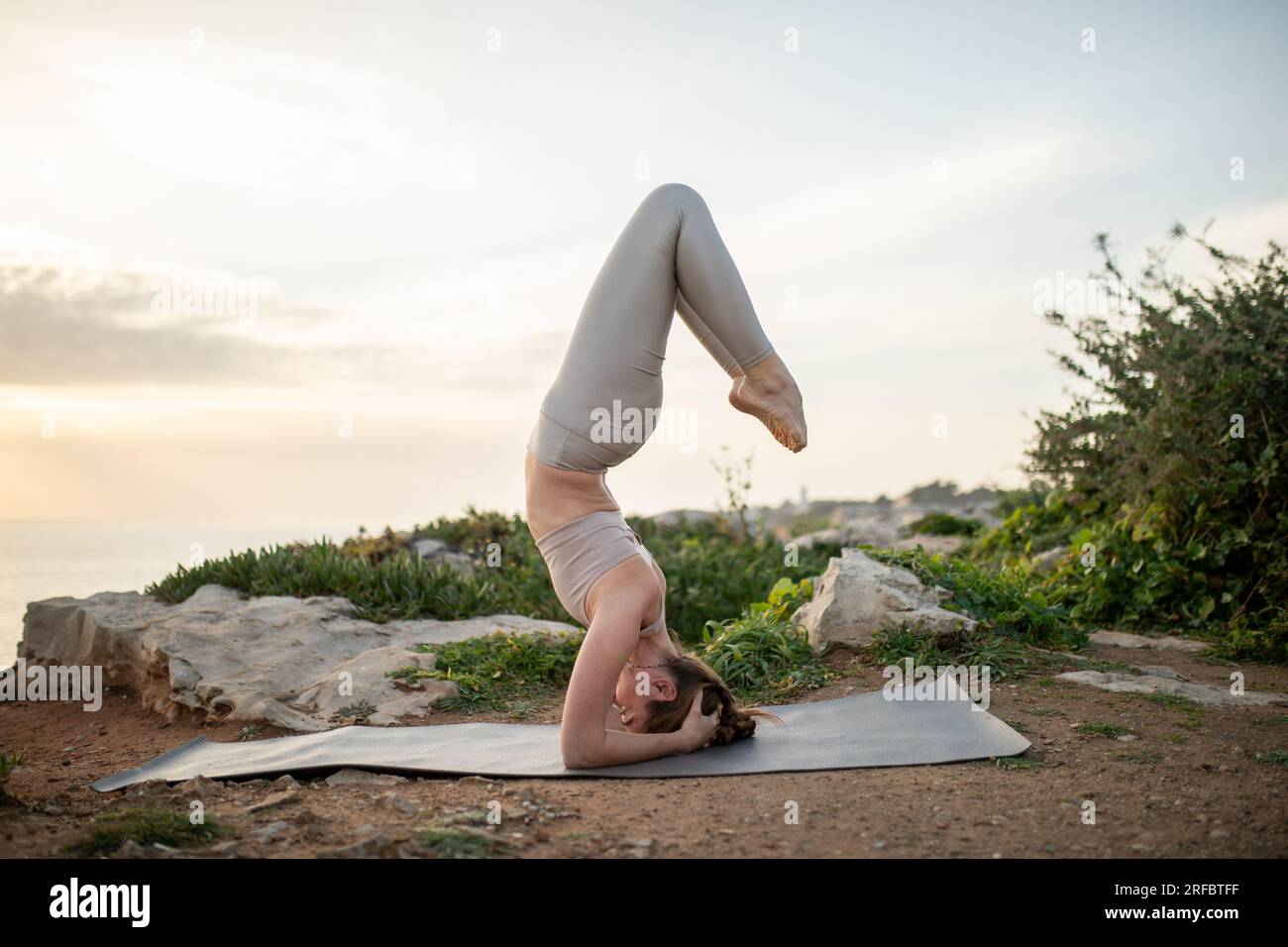 Calmo atleta donna caucasica millenaria che pratica yoga, fa asana sulla testa, si allena, ama lo sport Foto Stock