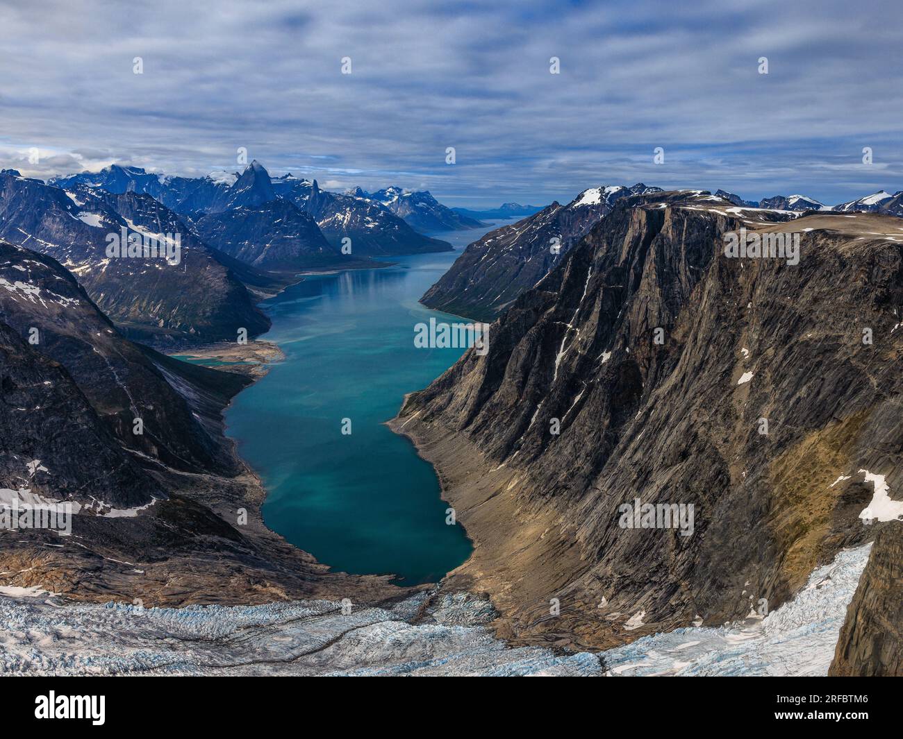 foto aerea dall'alto del ghiacciaio alla testa del fiordo di tasermiut in groenlandia con montagne rocciose che torreggiano sull'acqua del fiordo blu Foto Stock
