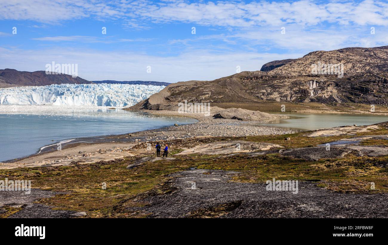 una morena laterale rocciosa separa un ghiacciaio sopra un mare di ghiaccio da una laguna interna con un'alta cascata Foto Stock
