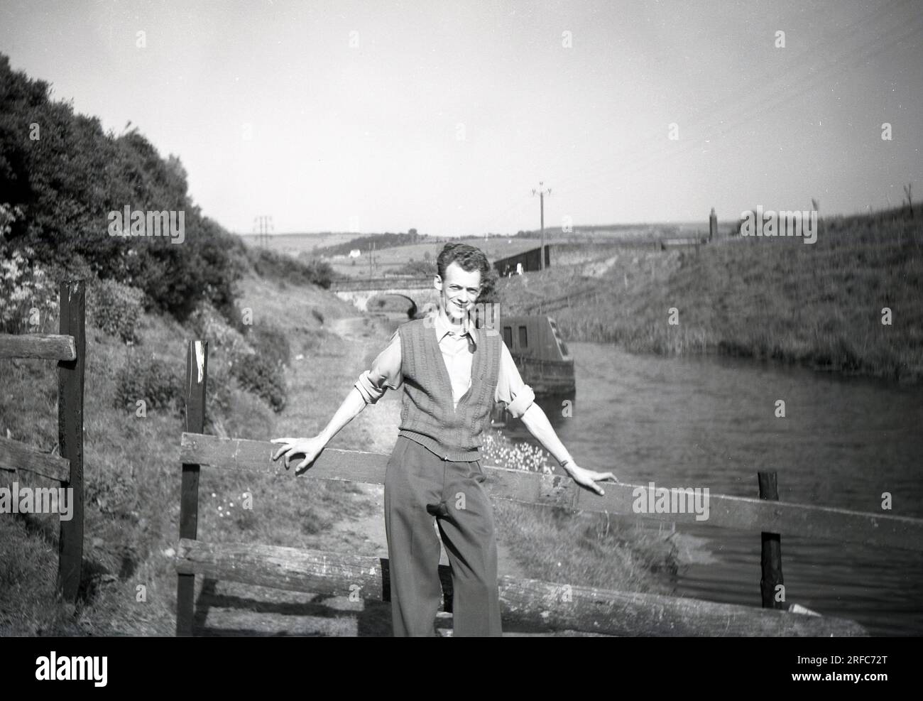 Anni '1950, storico, un uomo che indossa un cardigan senza maniche in cotone con zip, con pipa, in posa per una foto su un sentiero del canale Macclesfield, Cheshire, Inghilterra, Regno Unito. Foto Stock