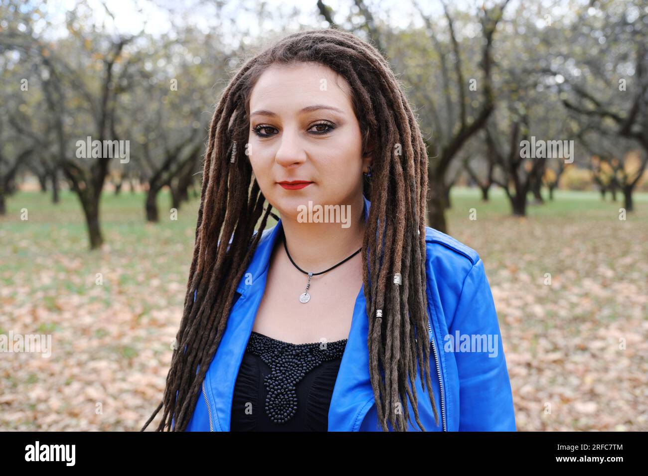Ritratto di una donna di mezza età con una giacca di pelle blu e dreadlocks. donna che guarda la telecamera. Foto orizzontale Foto Stock