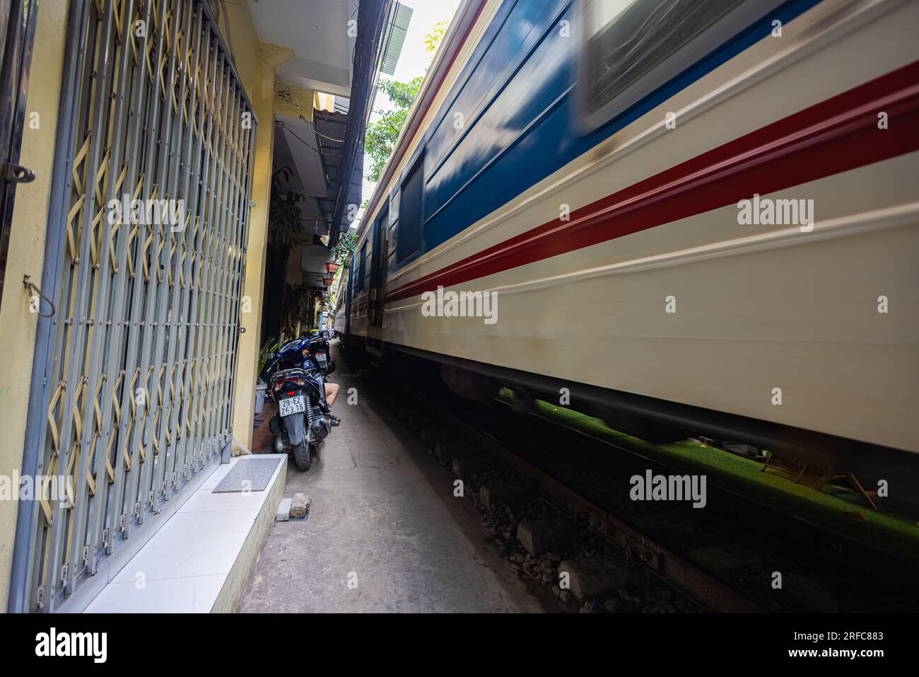 Hanoi, Vietnam - 28 maggio 2023: Train Street ad Hanoi è una stradina stretta e trafficata con binari. Case a maglia vicine, adornate di piante, distano pochi centimetri da qui Foto Stock