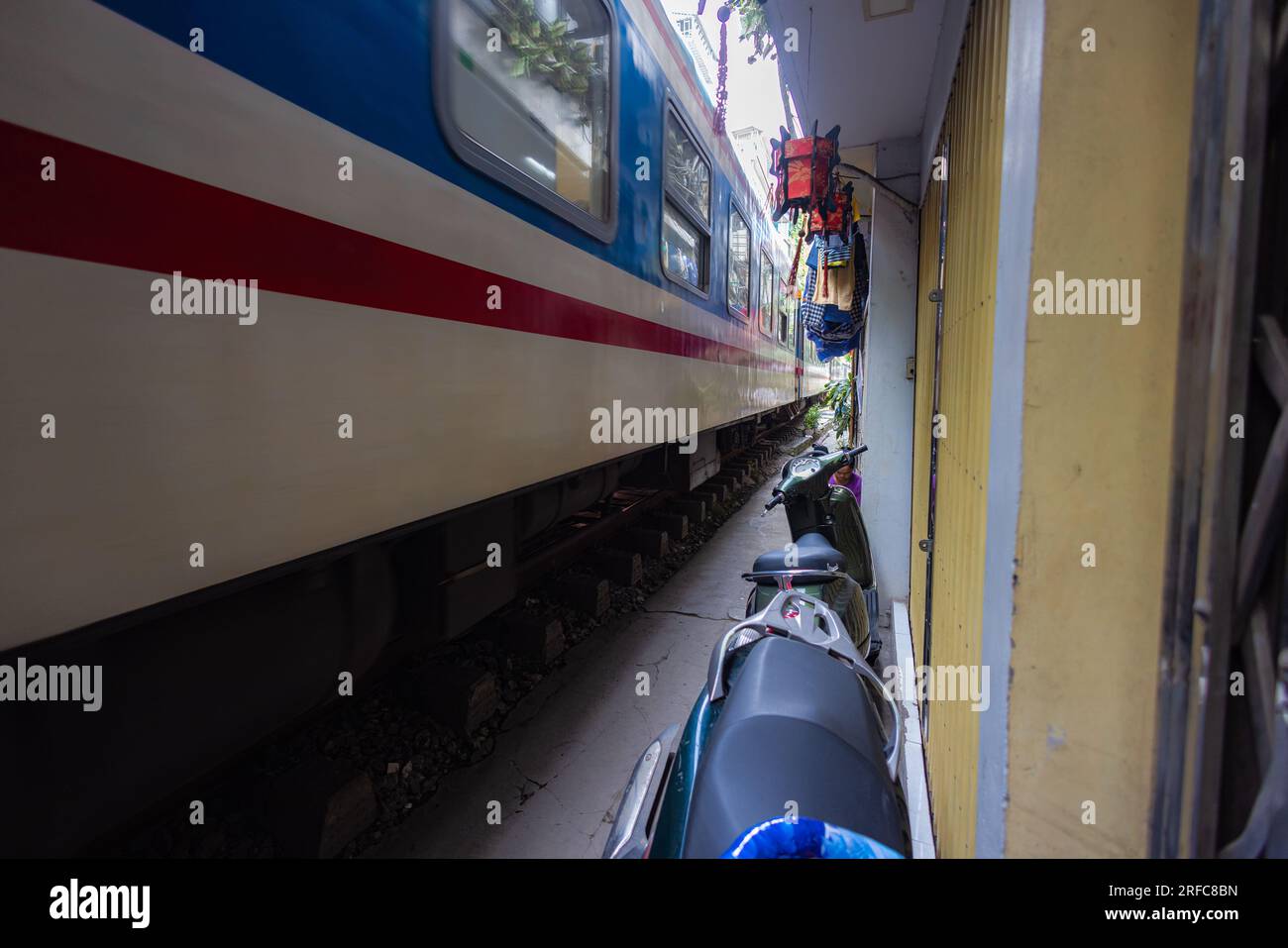 Hanoi, Vietnam - 28 maggio 2023: Train Street ad Hanoi è una stradina stretta e trafficata con binari. Case a maglia vicine, adornate di piante, distano pochi centimetri da qui Foto Stock