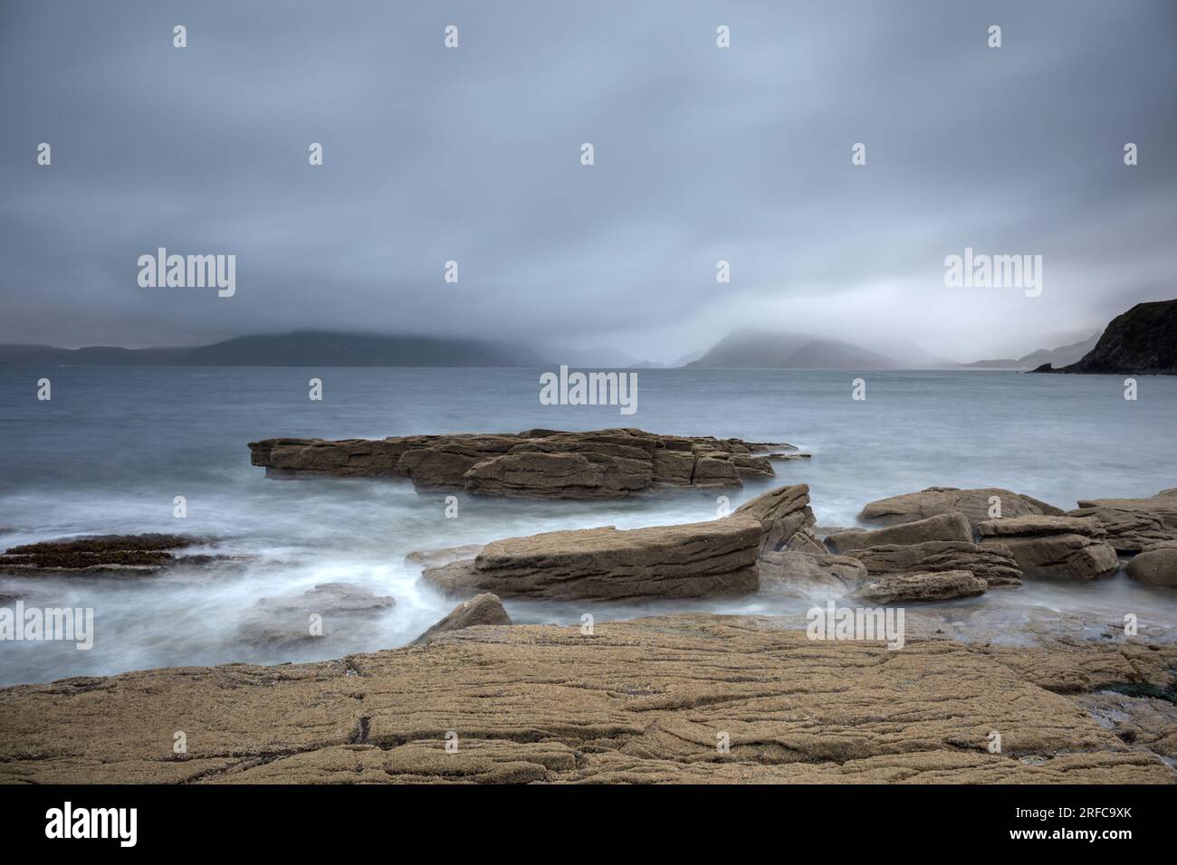 Costa rocciosa a Elgol, affacciata sul Loch Scavaig fino al Black Cuillin avvolto dalla nebbia Foto Stock