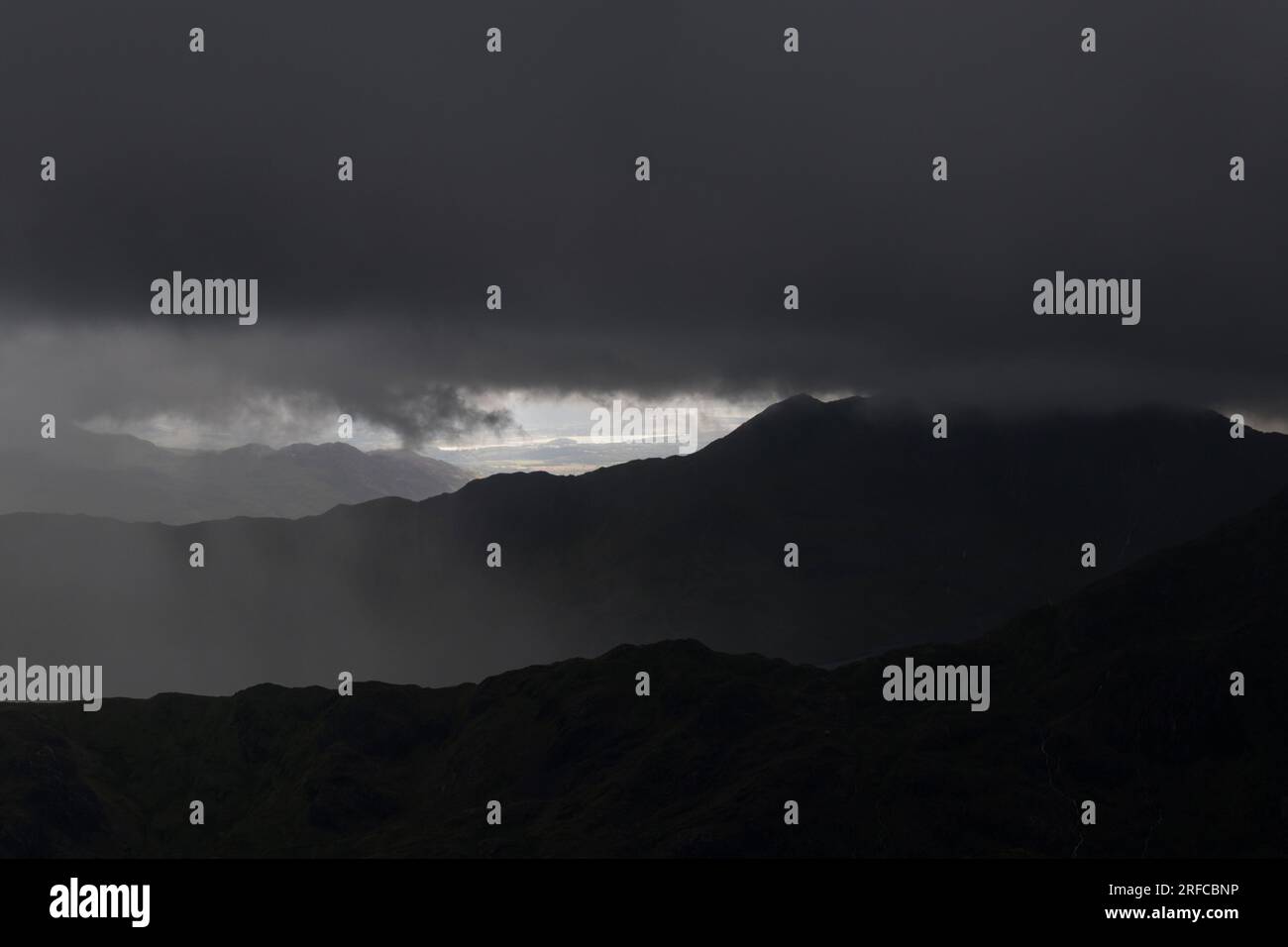 Guardando verso Snowdon velato in una fitta nuvola nera forma la cima del Glyder Fach, Snowdonia National Park, Galles Foto Stock