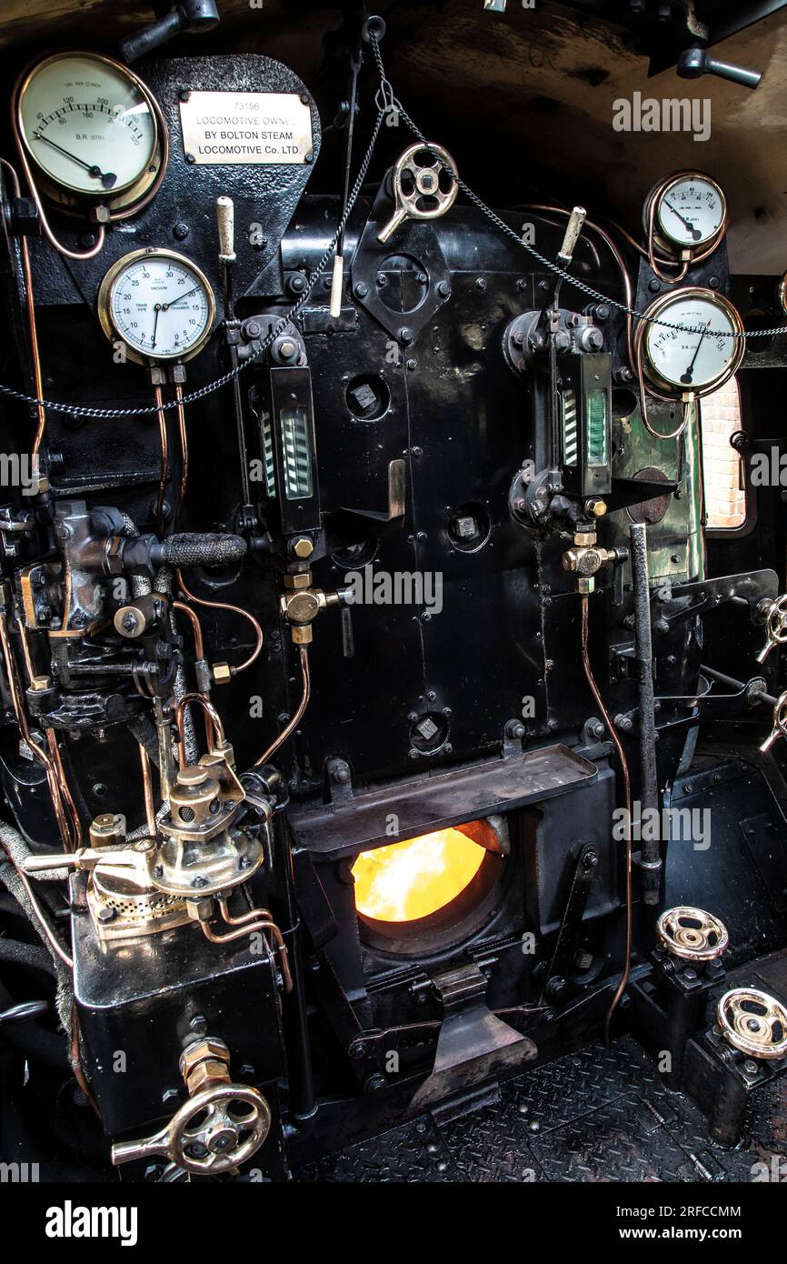 Una vista a pioli dei comandi, degli indicatori, dei livelli dell'acqua, del registratore di velocità e del firebox su una locomotiva a vapore standard 5MT British Railways Foto Stock