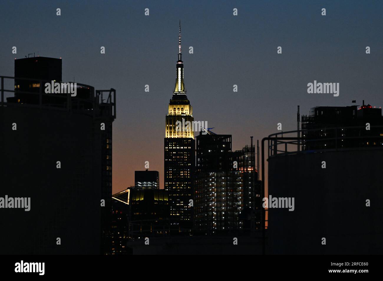 Il sole tramonta dietro l'Empire State Building e lo skyline di Manhattan il 1° agosto 2023 a New York City. Foto Stock