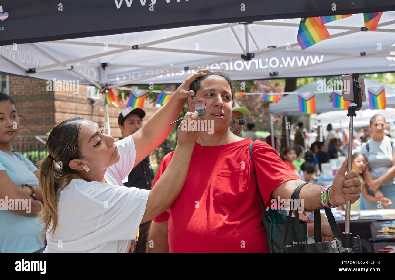 Al Transfest una trans fa un selfie mentre il transfalg le viene dipinto sulla guancia. A Jackson Heights, Queens, New York. Foto Stock