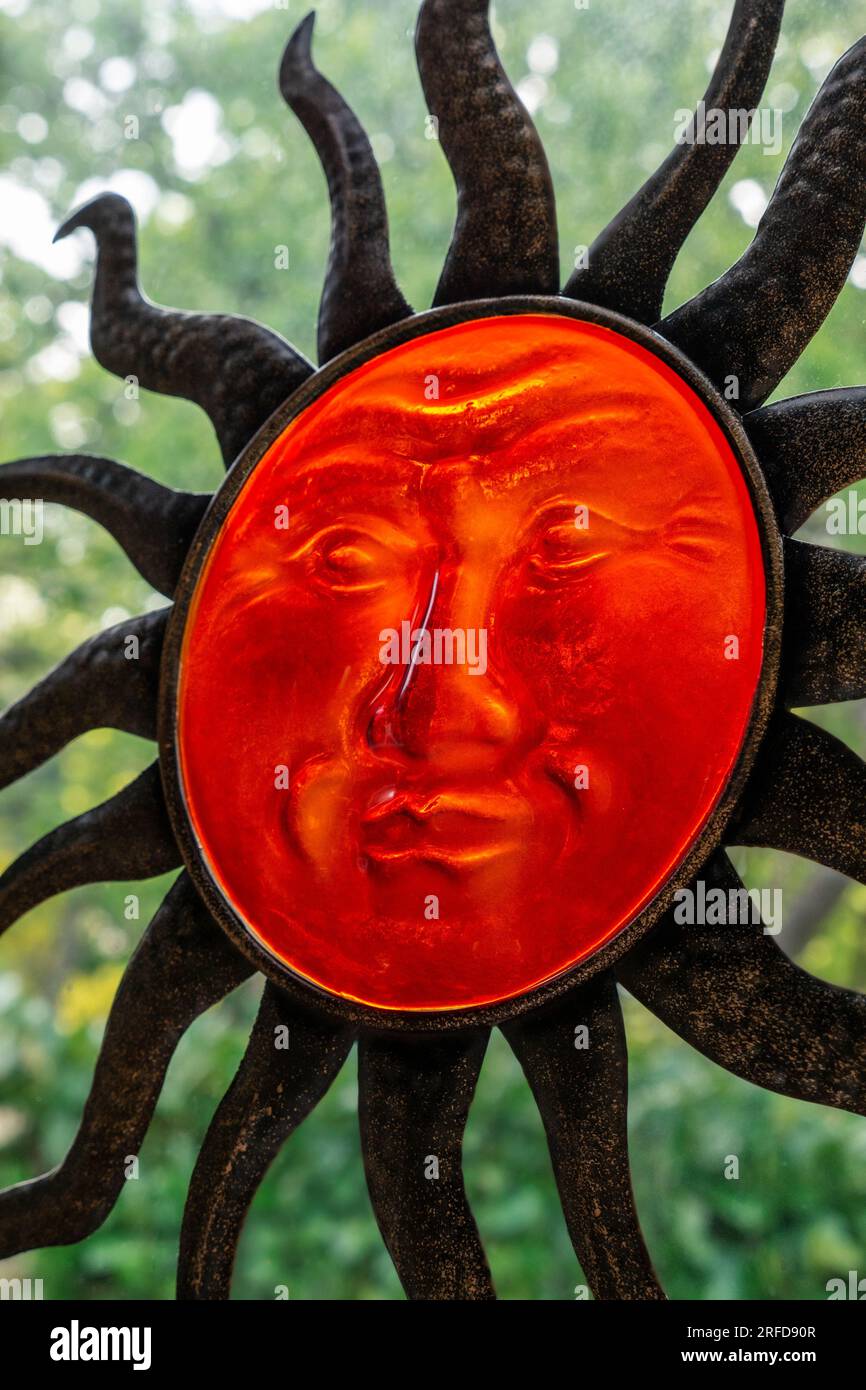 IL DIO DEL SOLE SI AFFACCIA SU una faccia in vetro traslucido di Inca Aztec il Dio del sole si AFFACCIA sul volto scultoreo e si estende con raggi di verde fogliame dietro Foto Stock