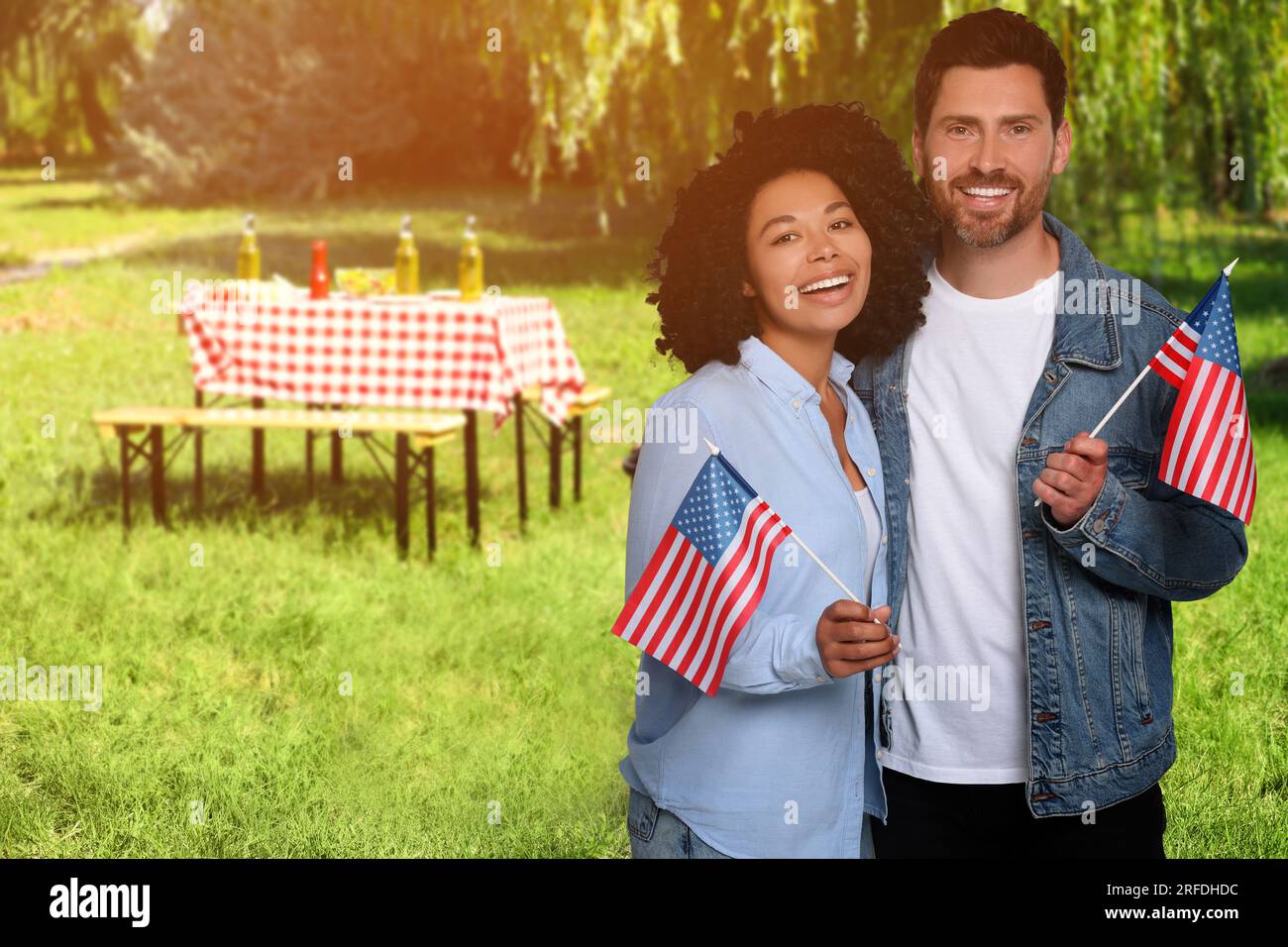 4 luglio - giorno dell'indipendenza dell'America. Felice coppia con bandiere nazionali degli Stati Uniti che fanno picnic nel parco Foto Stock