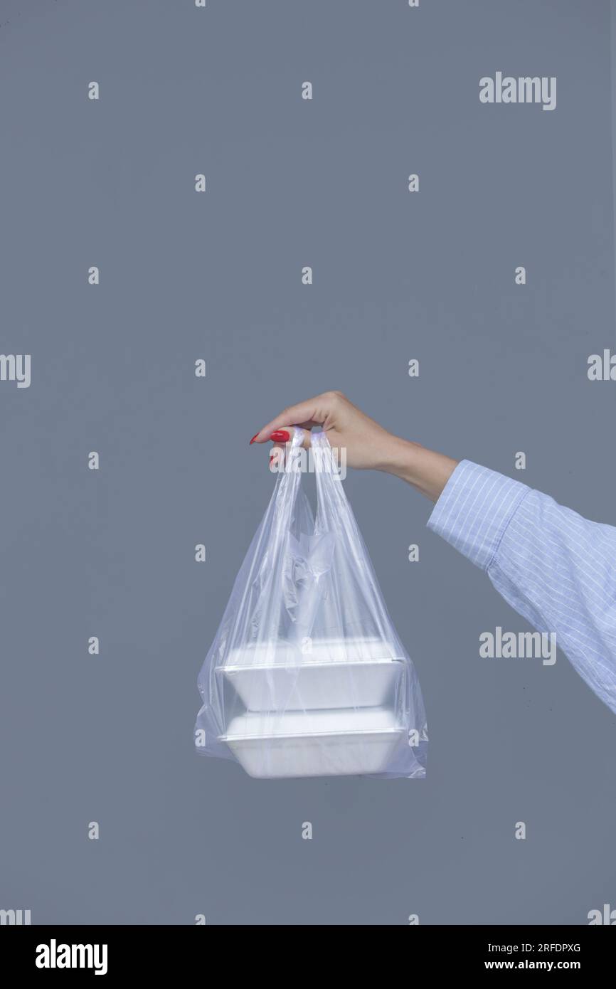 Donna che tiene una borsa in plastica PVC con portavivande in schiuma da asporto. Contenitori per alimenti monouso, concetto di donazione. Foto Stock