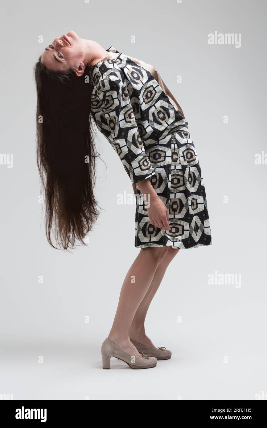negli anni '70, la giovane modella si piega alla schiena senza sforzo e i capelli lunghi raggiungono le ginocchia. Con uno sguardo impegnativo, mostra il suo fascino e la sua sicurezza Foto Stock