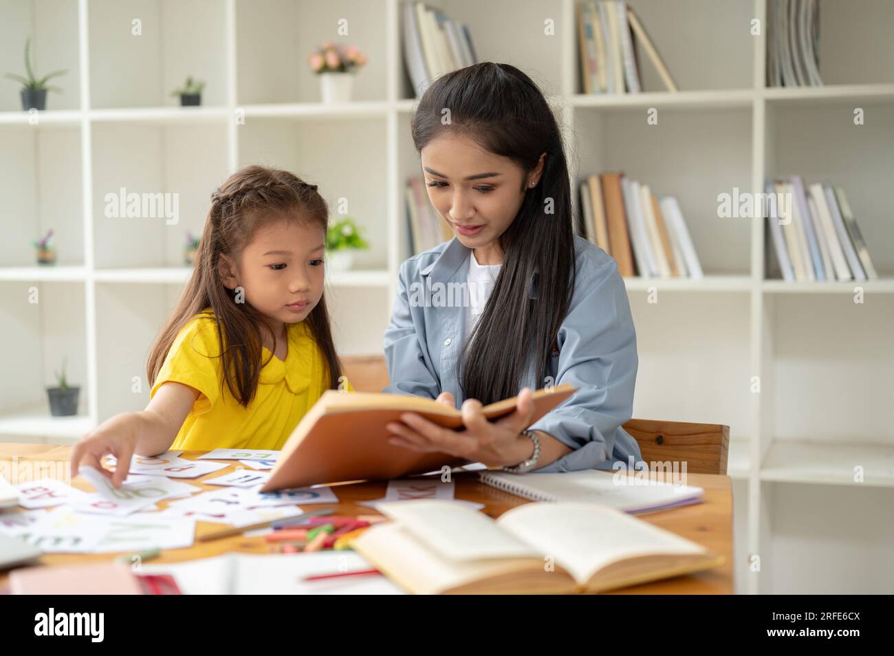 Una bella asiatica asiatica sta studiando l'alfabeto inglese su flashcard con un'insegnante gentile e premurosa. imparare, studiare, sviluppare bambini Foto Stock