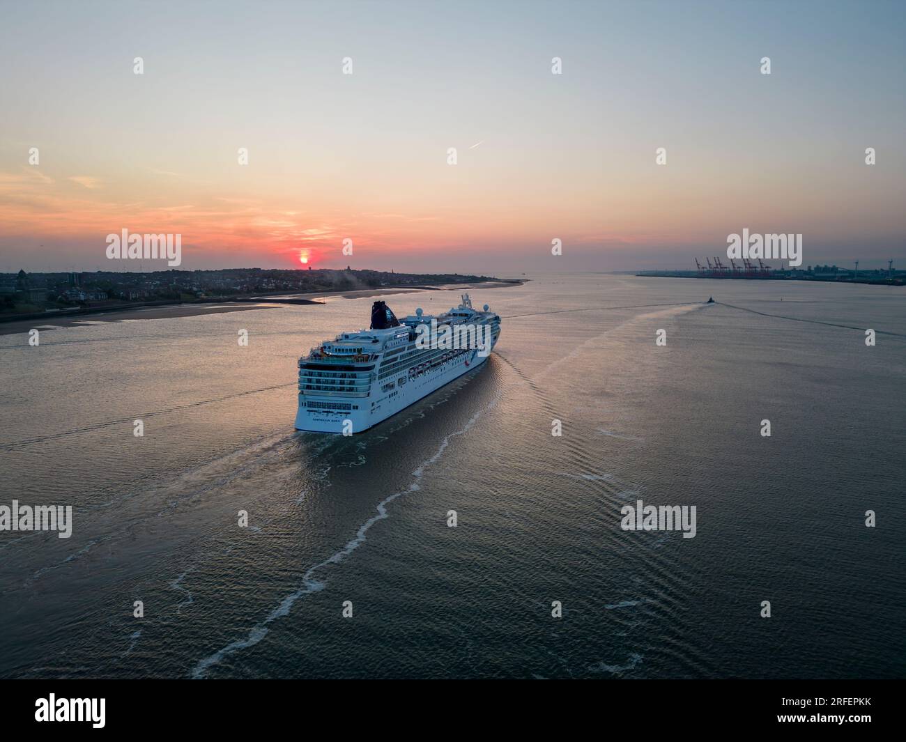 La nave da crociera Norwegian Dawn naviga lungo il fiume Mersey al tramonto, Liverpool, Inghilterra Foto Stock