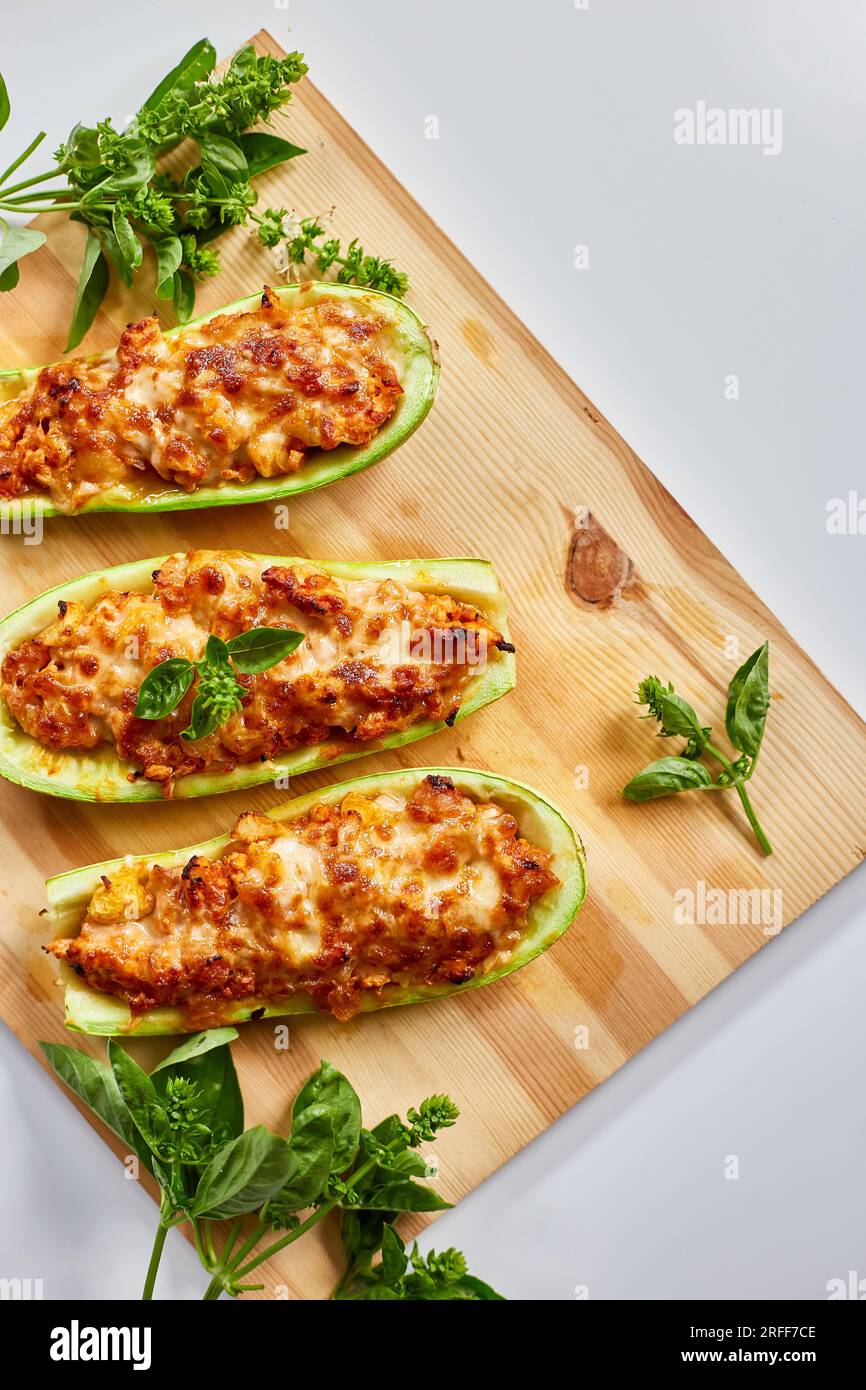 Zucchine ripiene su sfondo bianco, barche con zucchine al forno, vista dall'alto, fatte in casa. Foto Stock