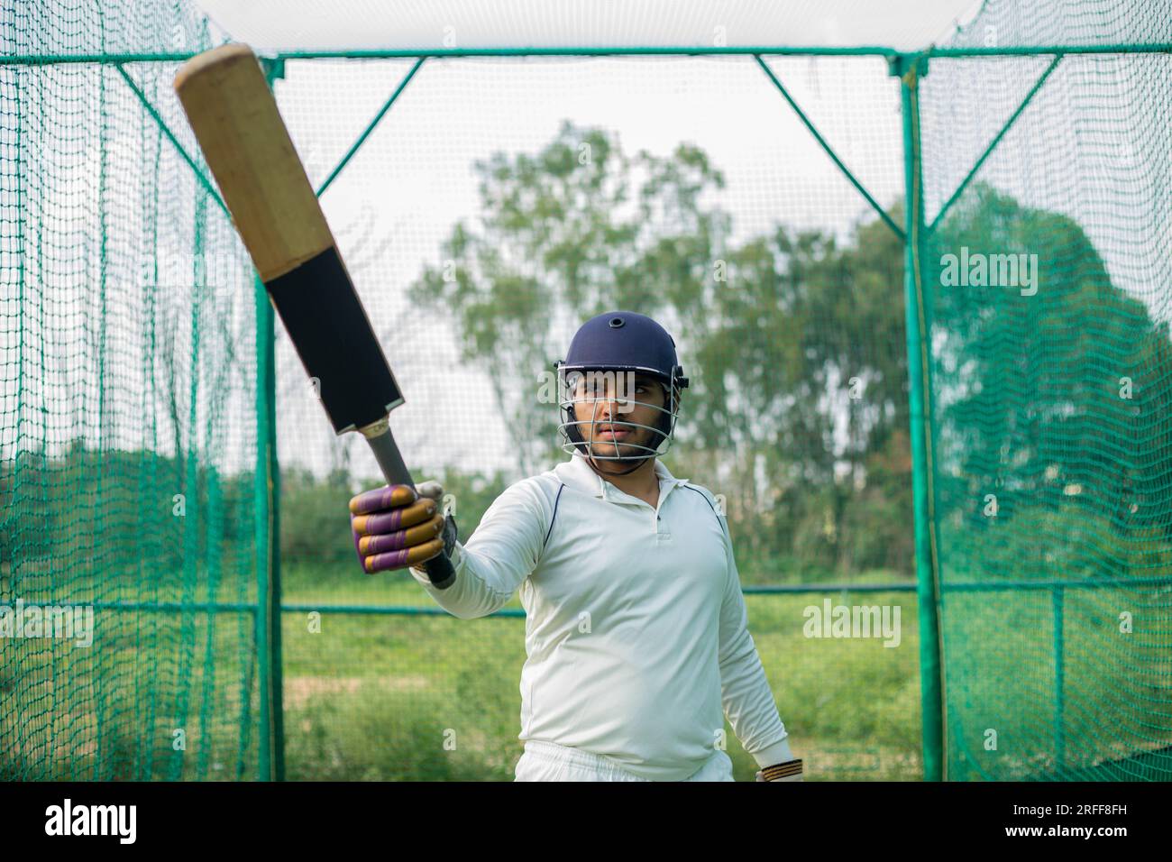 Il giocatore di cricket alza la sua mazza, celebrando un notevole risultato sul campo Foto Stock