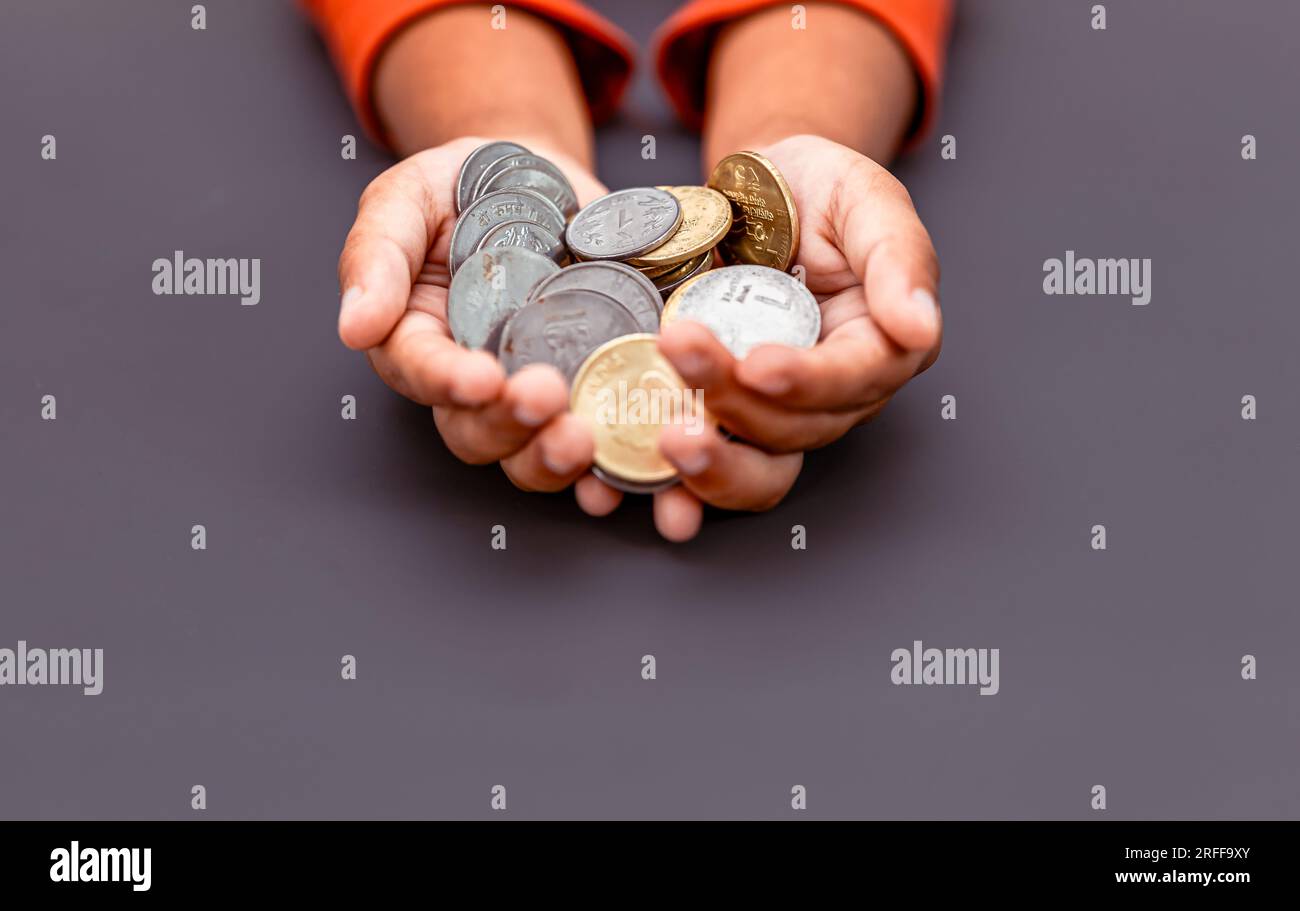 Un primo piano della mano di un bambino che regge una manciata di monete indiane. Foto Stock