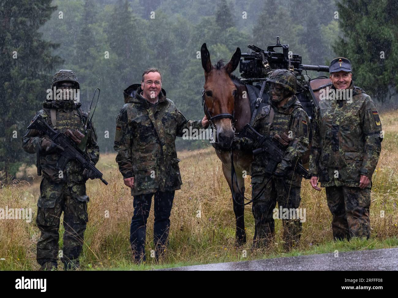 Bischofswiesen, Germania. 3 agosto 2023. Il ministro della difesa Boris Pistorius (2° da sinistra, SPD) si trova accanto a un mulo di trasporto sotto la pioggia battente durante la sua visita alla Brigata di fanteria di montagna 23 a Bad Reichenhall e Bischofswiesen. Il generale di brigata Michael Bender è sulla destra. Crediti: Peter Kneffel/dpa/Alamy Live News Foto Stock