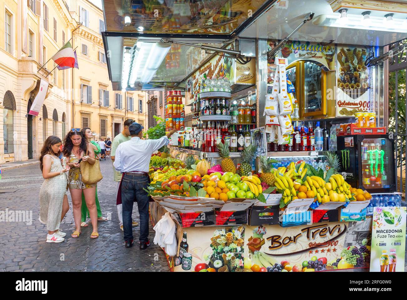 Roma, Lazio, Italia, turisti che acquistano succhi di frutta in un negozio di succhi di frutta con vari tipi di frutta in via Roma. Foto Stock