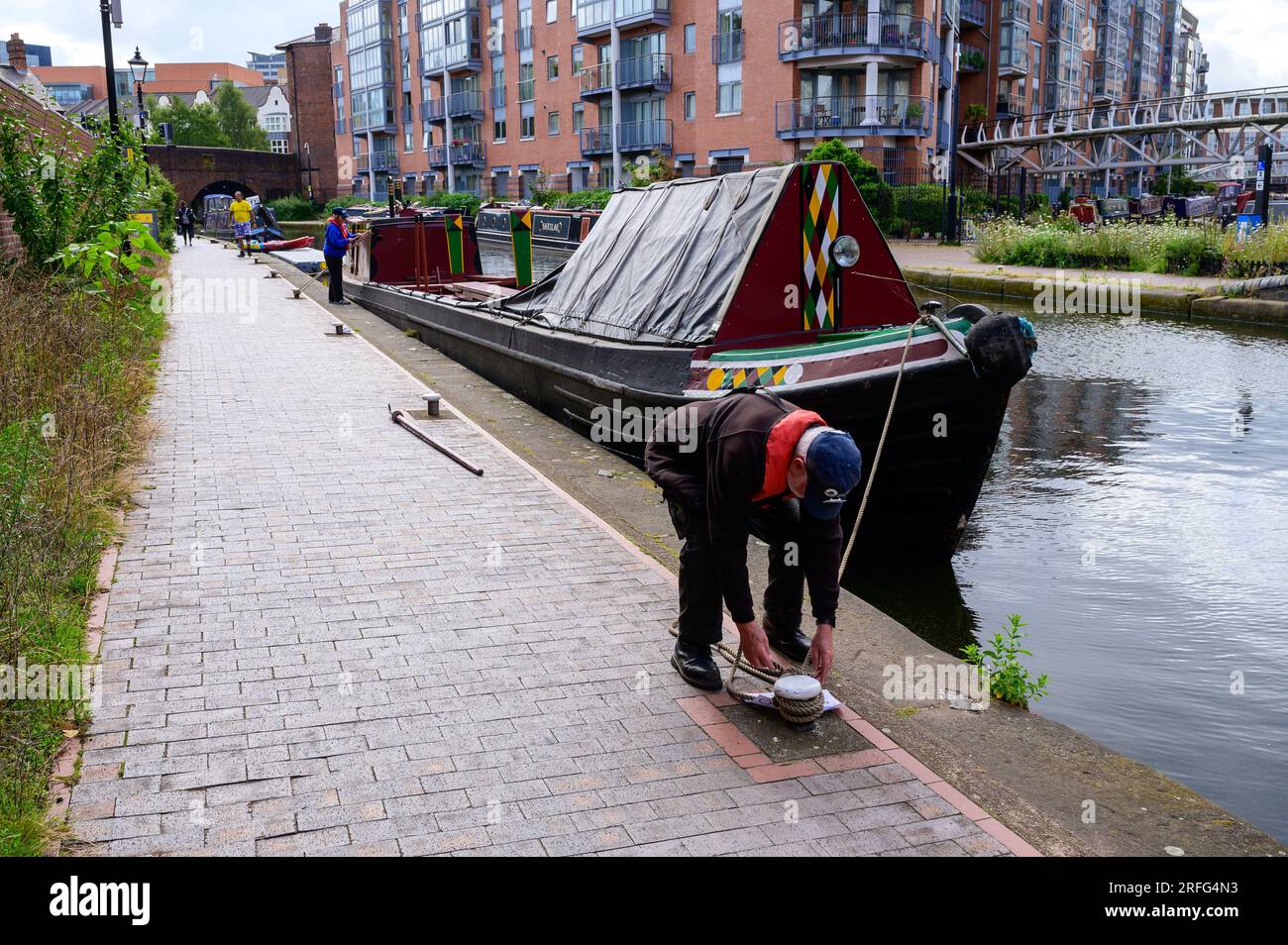 Membro dell'equipaggio che ormeggia sulla storica Narrwoboat Swift prima di portare i passeggeri in un viaggio su un canale di Birmingham Foto Stock