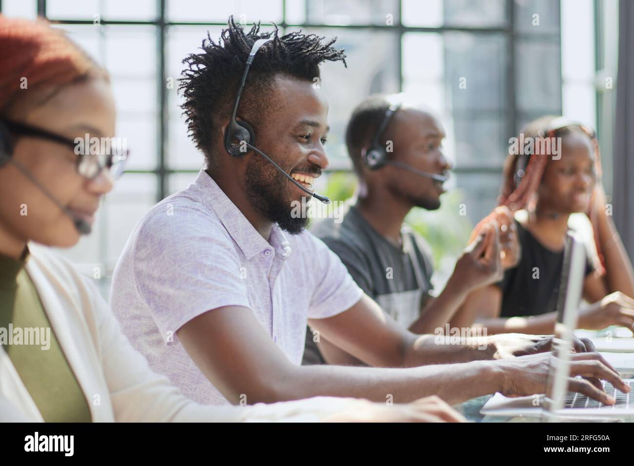 i giovani operatori di call center si siedono davanti a un computer portatile e aiutano a risolvere i problemi Foto Stock