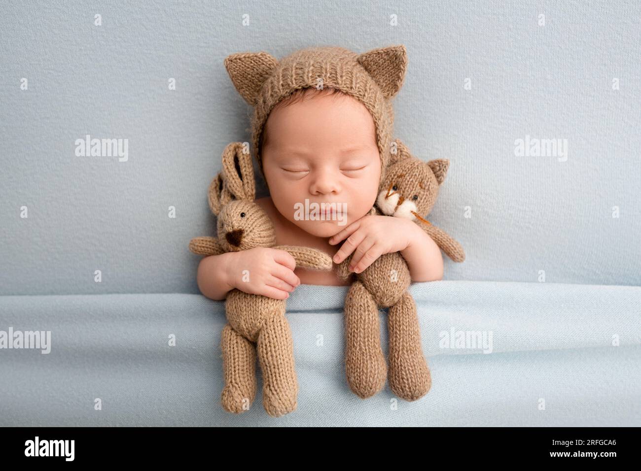 Nei primi giorni di vita, un simpatico neonato dorme in un cappello marrone con orecchie di gatto Foto Stock